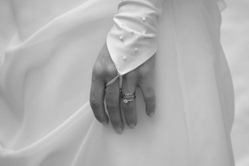 hochzeitsfotografie schwarz-weiss detail der braut, linke hand mit ring vor weissem kleid