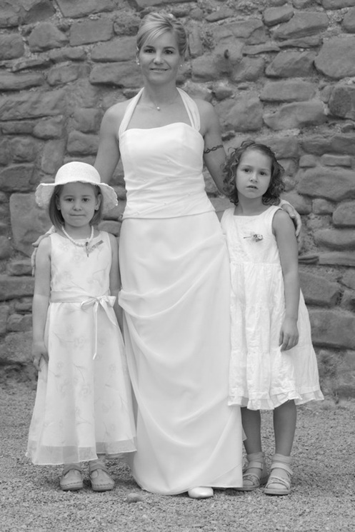 hochzeitsfotografie schwarz-weiss braut in weissem kleid mit zwei blumenmädchen vor steinwand