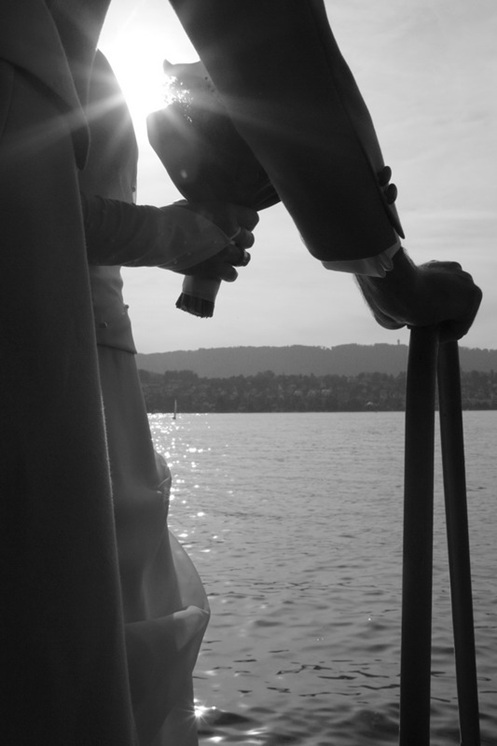 hochzeitsfotografie schwarz-weiss brautpaar ausschnitt im gegenlicht vor see mit brautstrauss