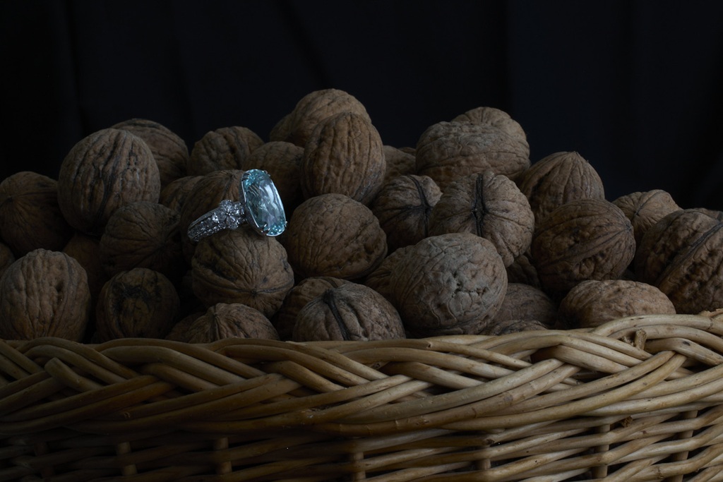 still life mit fingerring mit grossem hellblauem stein mit Diamanschliff auf korb mit baumnüssen