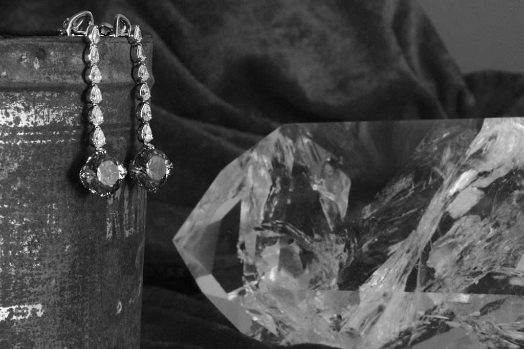 still life schmuck mit alter blechdose und kristall im hintergrund, schwarz-weiss fotografie