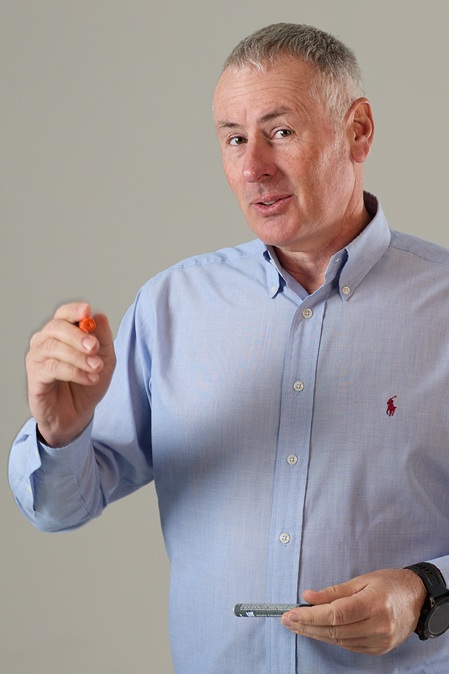 Herr um 50 Jahre mit hellblauem hemd und kurzem grauen haar mit stift in hand businessportrait marc keller