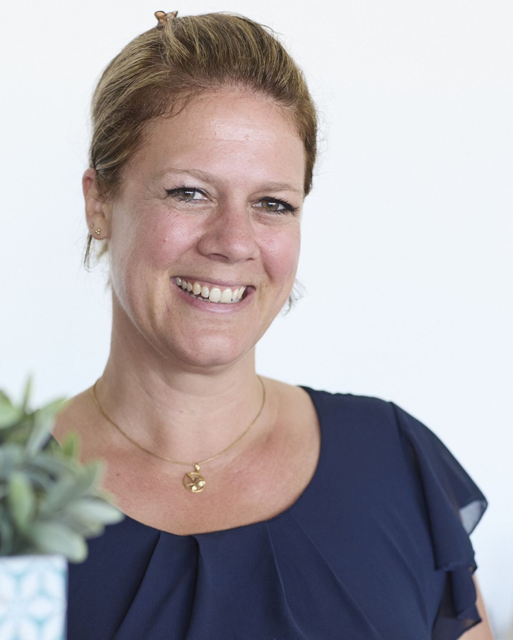frau mit dunkelblauem kleid schaue zufrieden lächelnd in die kamera