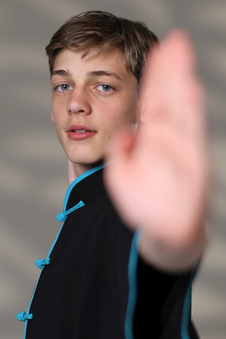 junger mann in kampfsport pose mit gegen die kamera gerichtete offene hand